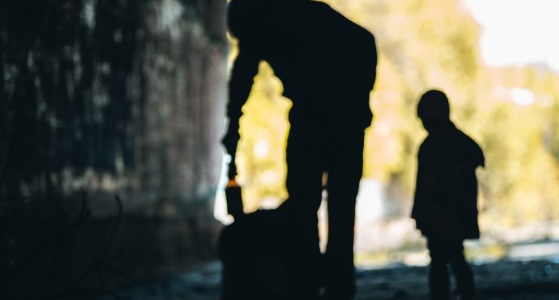 Silhouette of a man and child collecting goods.