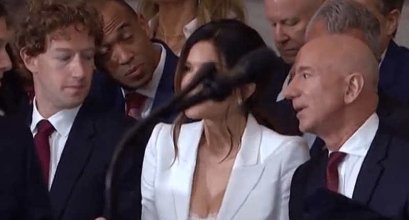 Group of people seated, some looking at a woman speaking into a microphone.