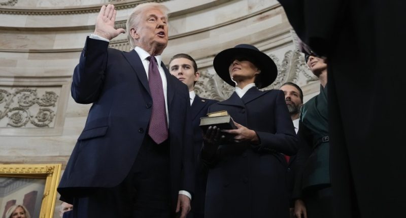 Donald Trump being sworn in as president, with Melania Trump holding a Bible.
