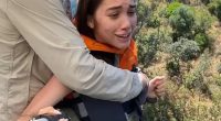 A reluctant woman is pushed off a bridge during a bungee jump.