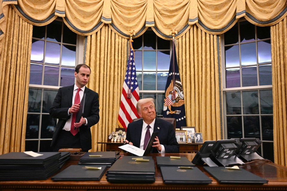 President Trump signing executive orders in the Oval Office.