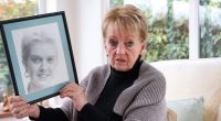 Woman holding framed photo of her murdered daughter.