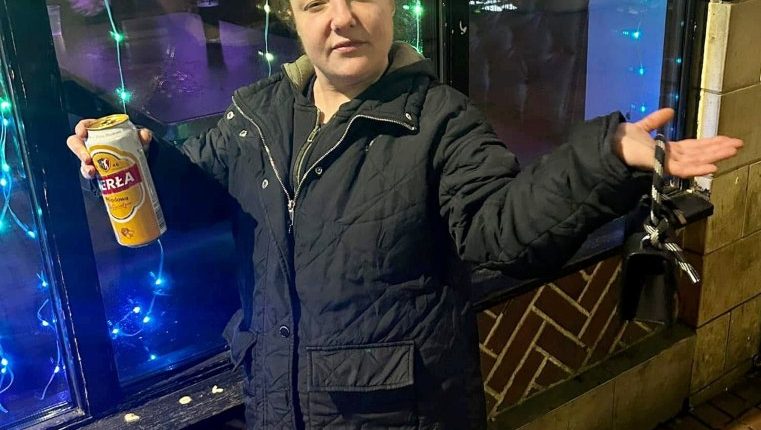 Woman holding a beer can outside at night.
