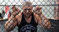 MMA fighter Maxim Novoselov behind a chain-link fence.