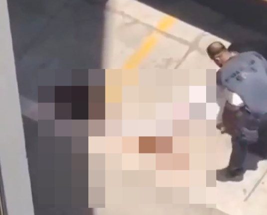 Video still showing a person lying on the ground while another person attends to them.