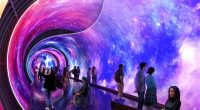 Illustration of a £220 million attraction: a tunnel with a galaxy-themed immersive display, people exploring the space.