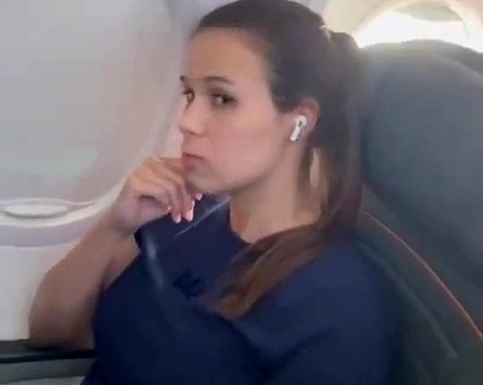 Video still of a woman on a plane refusing to switch seats with a crying child.