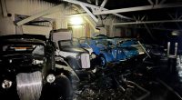 Bombed classic cars in a damaged building.
