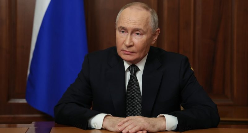 Vladimir Putin seated at a table, addressing the Russian armed forces.