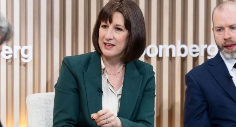 Woman in green jacket speaking at Bloomberg event.