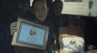 Two women in a car holding certificates from the Qassam Brigades.