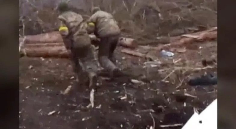 Soldiers forcing Ukrainian prisoners of war to their knees.