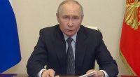 Vladimir Putin reading a document at a government meeting.