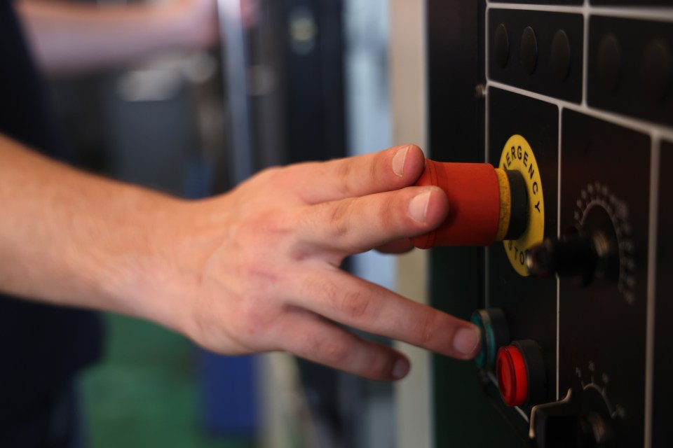 A hand pushing an emergency stop button.