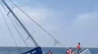 Catamaran sinking with passengers being rescued.