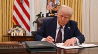 President Trump signing an executive order in the Oval Office.
