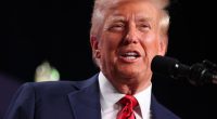 Donald Trump speaking at a microphone.