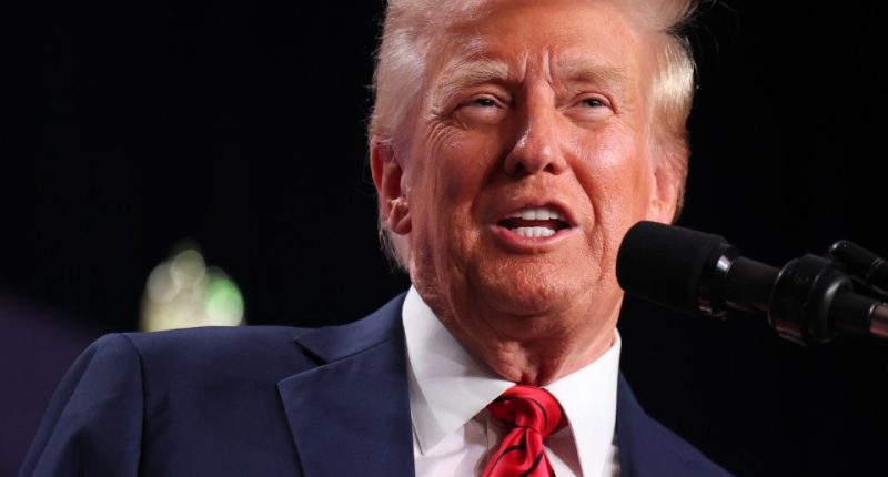 Donald Trump speaking at a microphone.