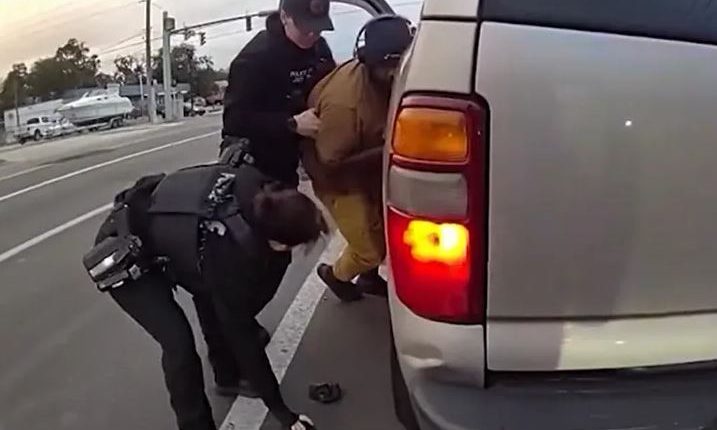 Police officers arresting a suspect next to his SUV.