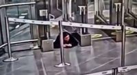 Security footage of a woman crawling under an airport security barrier.