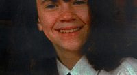 Photo of a girl smiling, wearing a white shirt and tie.