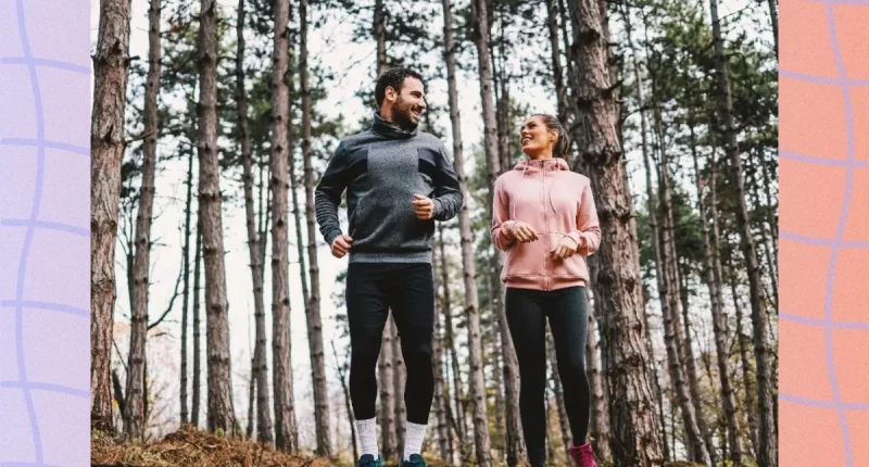 fit couple smiling and looking at each other as they prepare to go for a light jog or brisk walk in the woods