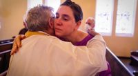 A congregant is hugged by a priest during a religious service in the aftermath of the Eaton Fire at Trinity Lutheran Church Sunday, Jan. 12, 2025 in Pasadena, Calif. (AP Photo/Ethan Swope)