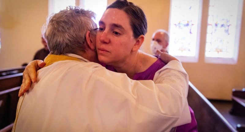 A congregant is hugged by a priest during a religious service in the aftermath of the Eaton Fire at Trinity Lutheran Church Sunday, Jan. 12, 2025 in Pasadena, Calif. (AP Photo/Ethan Swope)