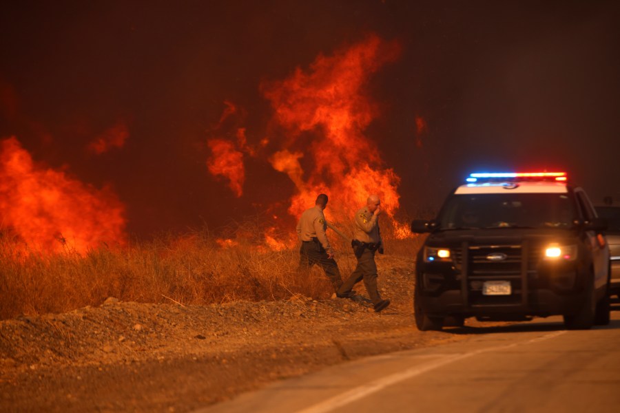 County Sheriff officers return to their vehicle during the Hughes Fire in California Jan. 22, 2025.