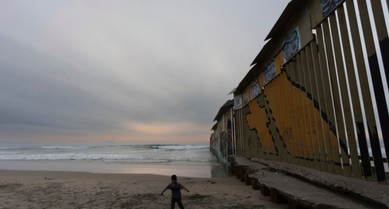 A boy walks near where a border wall separating the United States from Mexico reaches the Pacific Ocean, Tuesday, Nov. 26, 2024, in Tijuana, Mexico. (AP Photo/Gregory Bull)