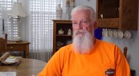A man in an orange shirt describes his experience with a broken couch.
