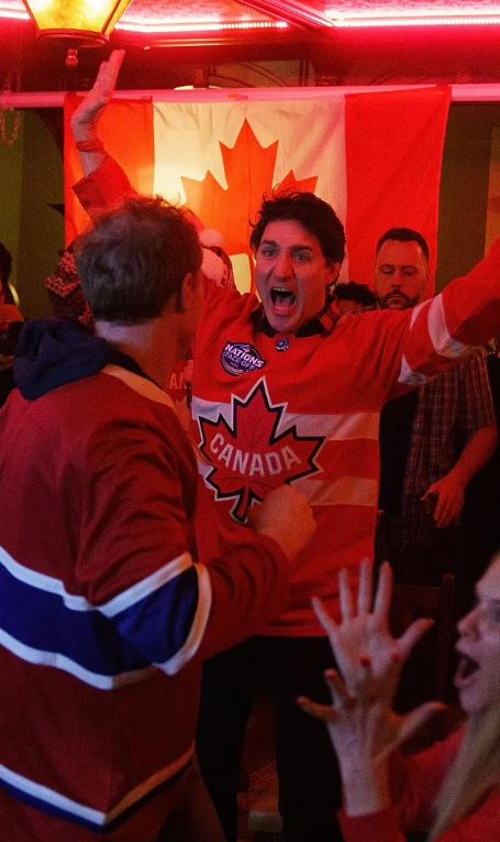 Justin Trudeau wearing a Canada hockey jersey and celebrating.
