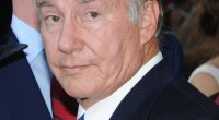 Headshot of an older man in a suit and blue tie.