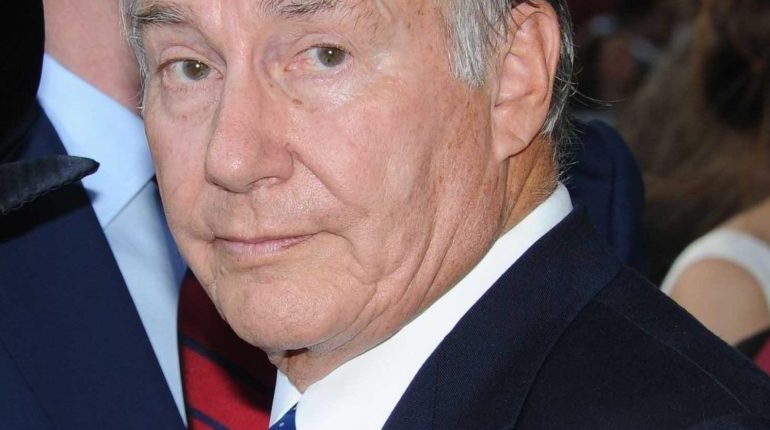 Headshot of an older man in a suit and blue tie.