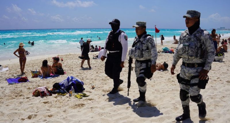 Mexican Navy and National Guard patrolling a beach with spring breakers.