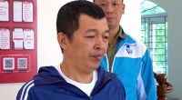 A man in a blue jacket being detained by police.