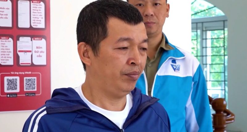A man in a blue jacket being detained by police.
