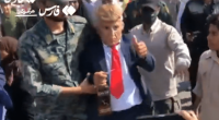 Person in a Donald Trump mask escorted by soldiers.