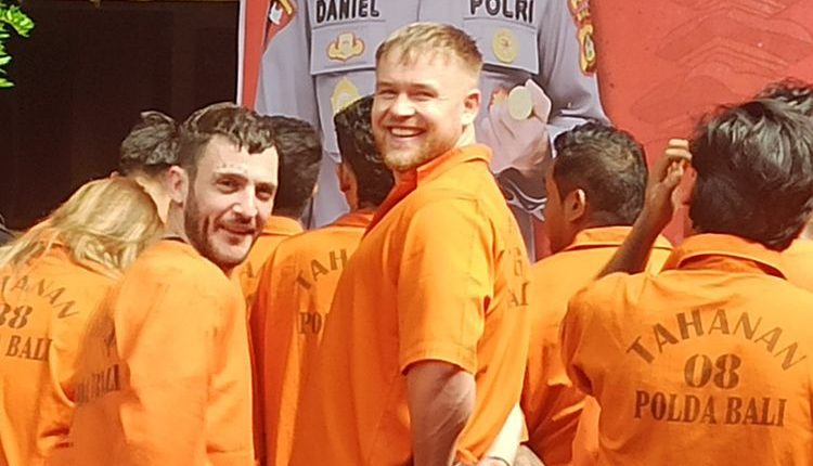 Three British tourists in orange prison jumpsuits at a press conference.