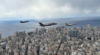 Three Israeli warplanes flying low over a city near the coast.