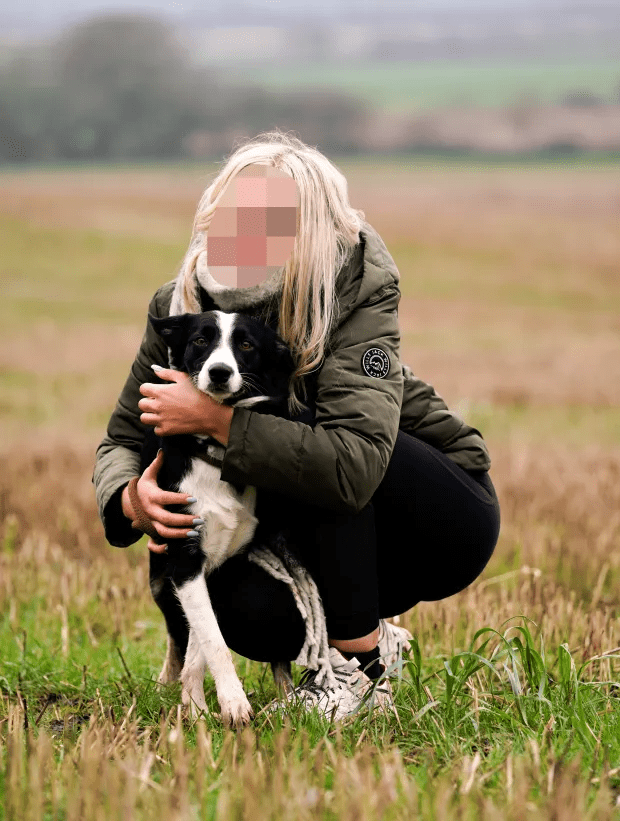 Woman crouching and hugging her border collie in a field.