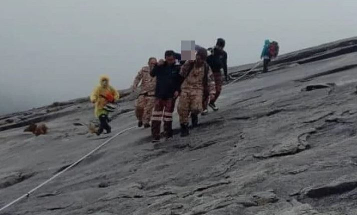 Rescuers carrying an injured climber down a mountain.