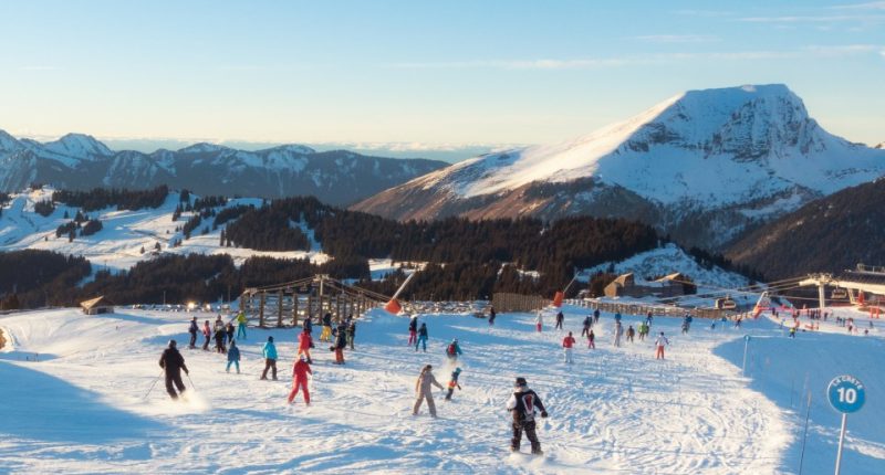 Skiers and snowboarders on a sunny blue piste in the Avoriaz/Morzine ski area.