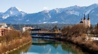 River reflecting snow-capped mountains and a church.
