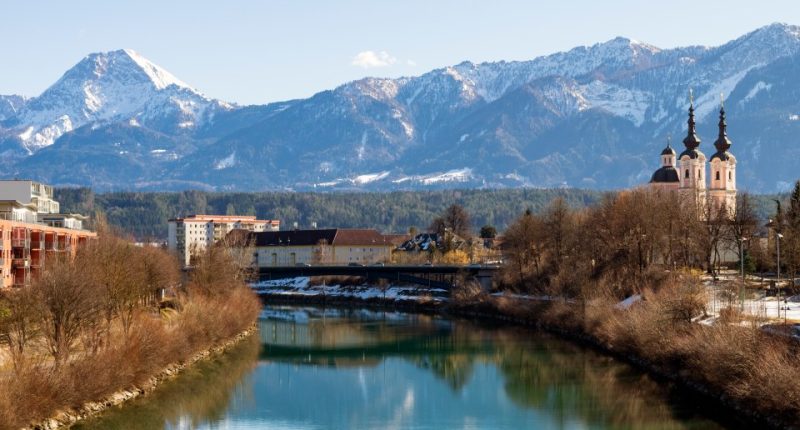 River reflecting snow-capped mountains and a church.