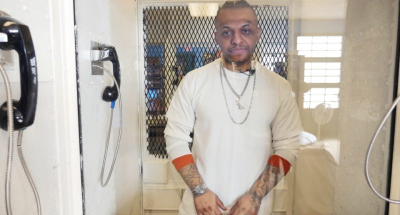 A death row inmate in a prison visiting booth.