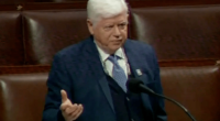 Man in suit speaking at a podium.
