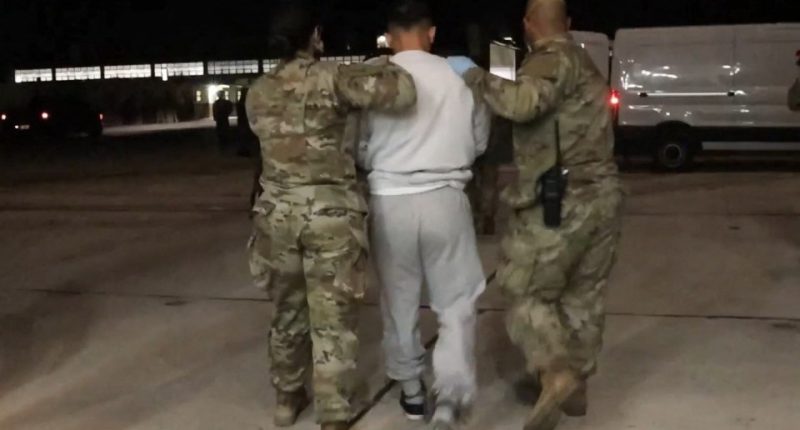 Screenshot of detained migrants arriving at Guantanamo Bay.