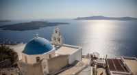 Santorini church with blue dome overlooking the Aegean Sea.