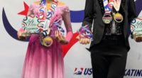 Two young figure skaters holding medals and trophies.